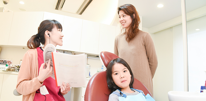 患者様とお子様に治療内容を説明するスタッフ